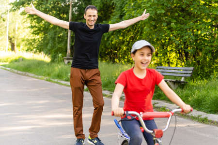 happy father rejoices that her daughter learned to ride a bikeの写真素材