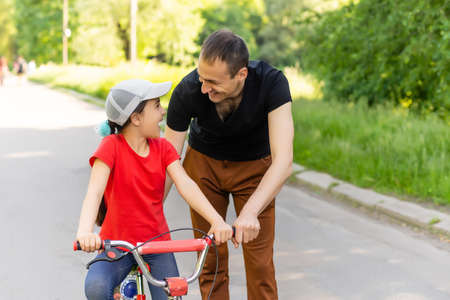 loving father teaching daughter to ride bikeの写真素材