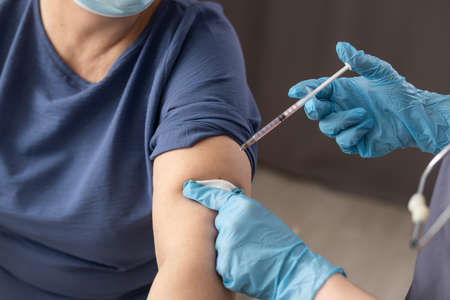 Senior woman receiving vaccine. Medical worker vaccinating an elderly patient against flu, influenza, pneumonia or virus.の写真素材