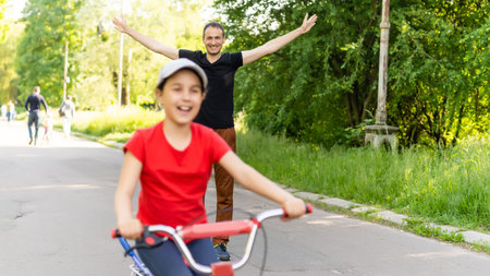 happy father rejoices that her daughter learned to ride a bikeの写真素材