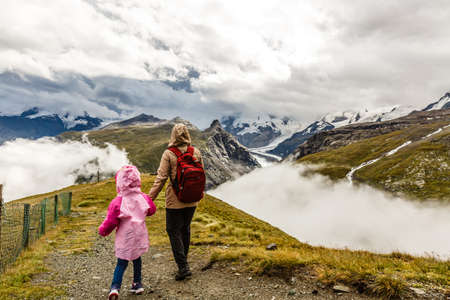 Hikers with backpack looking at mountains, alpine view, mother with childの写真素材