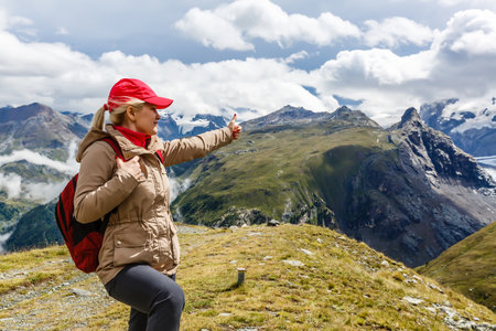 Young happy woman with backpack standing on a rock and looking to a valley belowの写真素材