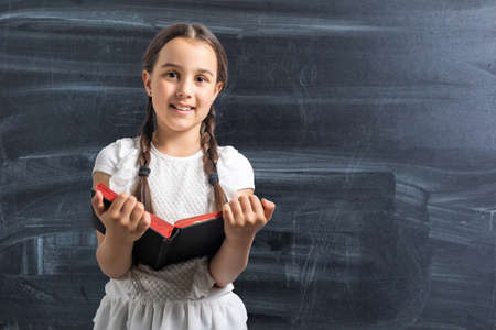 Brunette little girl reading a book isolated on a over white backgroundの写真素材