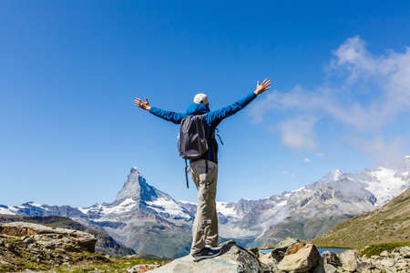 Hiking in the swiss alps with flower field and the Matterhorn peak in the background.の写真素材