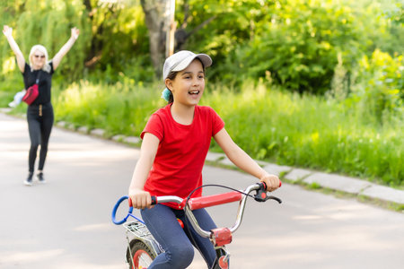 Front view portrait of caucasian mother looking through her glasses while helping her daughter to ride the bikeの写真素材