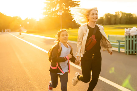 Mom and schoolgirl of primary school holding hands. The parent takes the child to school. Outdoors, return to the concept of the schoolの写真素材