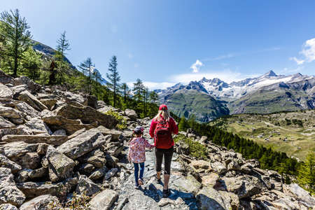 Happy family with little child doing trekking on switzerland mountain in summer time. Young people having fun in landscape nature. Concept of travel, friendly familyの写真素材