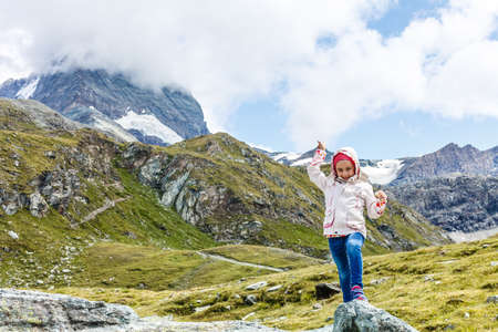 Children hiking in Alps mountains. Kids look at mountain in Austria. Spring family vacation. Outdoor fun and healthy activity.の写真素材