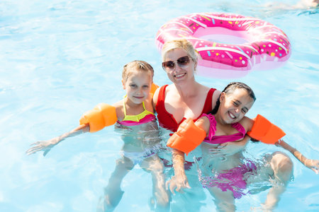 Woman teaching little girl to swim. Place for text.