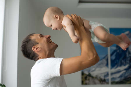 Father Hugging Newborn Baby in white bedroom.の写真素材