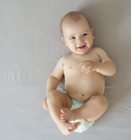 Adorable baby boy in white sunny bedroom. Newborn child relaxing in bed. Nursery for young children....