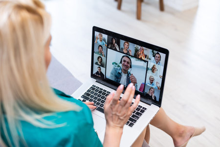 Woman having video chat with colleagues at table in office, closeup