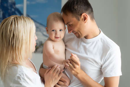 A Happy young family with baby in white bedroomの写真素材