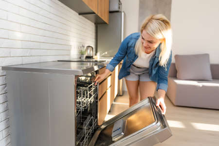 side view of young woman in kitchen doing houseworkの写真素材
