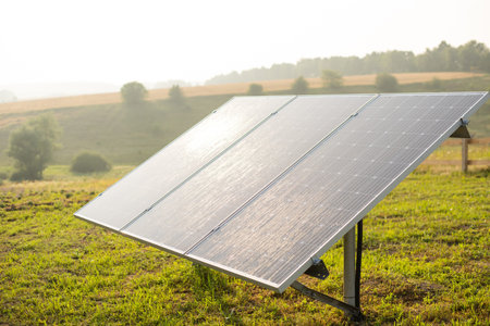 Solar panel on blue sky background. Green grass and cloudy sky. Alternative energy concept
