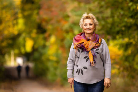 Senior woman walking in the park in autumnの写真素材