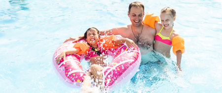 Active father teaching his children to swim in pool on tropical resort. Summer vacations and sport...