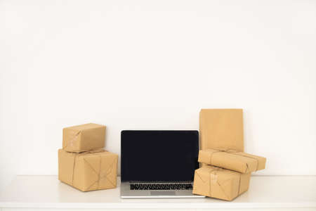 laptop computer at workplace of start up, small business owner, freelance, seller. cardboard parcel box of product for deliver to customer. Online selling, e-commerce, packing, shipping conceptの写真素材