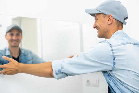 Handyman installing mirror in bathroom.の写真素材