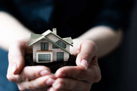 Model house in womans hand, boxes in the backgroundの写真素材