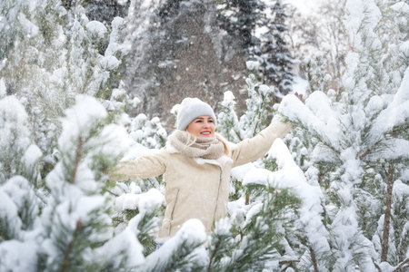 Young laughing happy Caucasian woman and pine branches in winter forest. Positive emotions, walking...