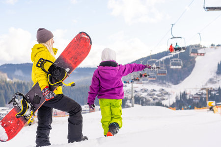 Mother and daughter with snowboards are playing in the snowの写真素材
