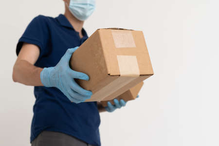 Delivery guy with protective mask and gloves holding box with groceriesの写真素材