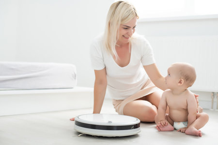 Robotic vacuum cleaner next to the baby girlの写真素材