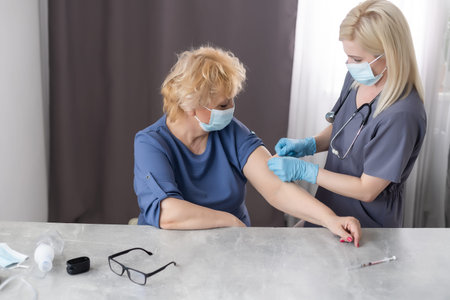 Doctors are vaccinating an elderly woman in a white shirt to build up the virus  immune system
