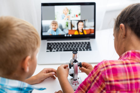 Boy and girl, brother and sister study at home. A girl watches a video lesson or an online...