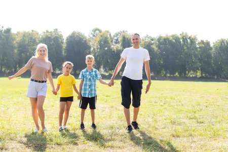 Happy family walking in field and holding hands