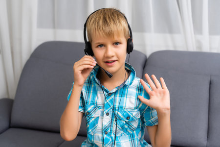 Close up screen view of small Caucasian boy child in headphones talk speak on video call at home....