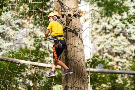Teenage girl goes on hinged trail in extreme rope Park in summer forest. High-altitude climbing...