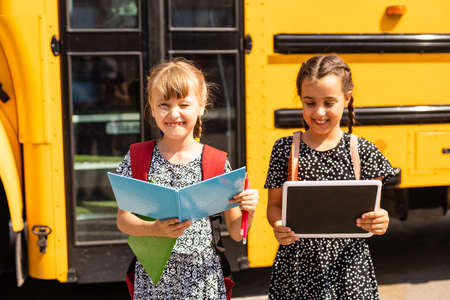 Portrait of two girls with school bags after lesson in schoolの写真素材