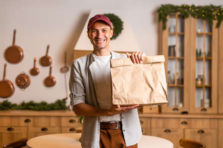 a delivery man with a package of food stands in a Christmas interiorの写真素材