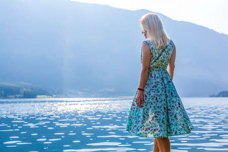 Young woman standing with backpack on cliffs edge and looking to a skyの写真素材