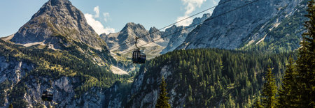 Two cabs of the cableway and skiers on the slope of the mountain Chopok south side on a sunny day in the skiの写真素材