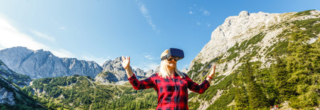 Girl in helmet virtual reality VR on the top mountain enjoing winter landscape