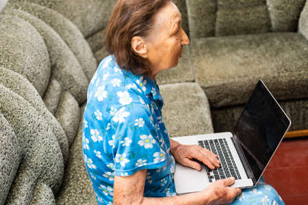 Senior woman looking at screen of laptop computer during video call from homeの写真素材