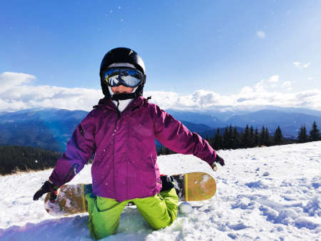 Snowboard Winter Sport. Little kid girl playing with snow wearing warm winter clothes. Winter backgroundの写真素材