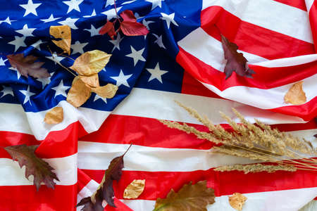 USA flag buried in yellow dry leaves. Autumn texture.の写真素材