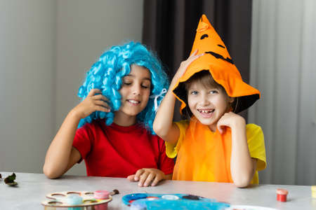 Halloween mood. two little girls are preparing for party, cutting decorations, making fall leavesの写真素材