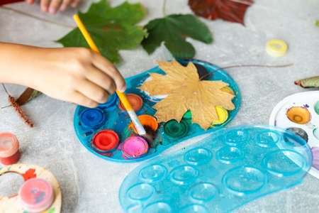 Child painting autumn leaves at homeの写真素材