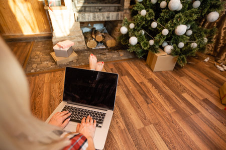 Happy woman looking in laptop in front of Christmas treeの写真素材