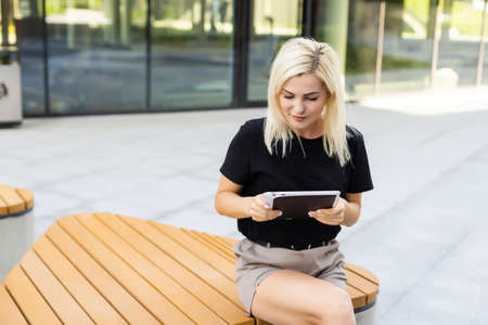 view of a young woman using a tablet computer on a park benchの写真素材