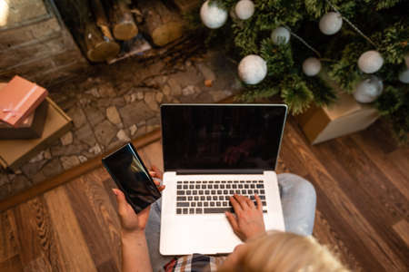 Happy woman looking in laptop in front of Christmas treeの写真素材