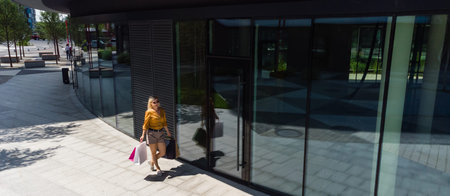 happiness, consumerism, sale and people concept - smiling young woman with shopping bags over mall...
