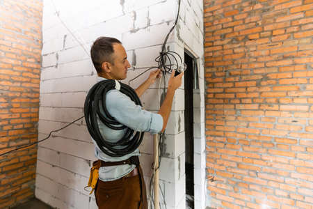 repairman in overalls wearing tool belt standing in building, renovation in the officeの写真素材