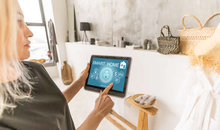 Woman use application for smart home control on tablet. Interior of living room in the background.の写真素材