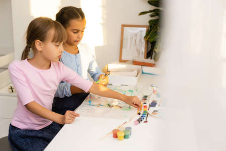 two schoolgirls draw leaves, girls paint autumn leavesの写真素材